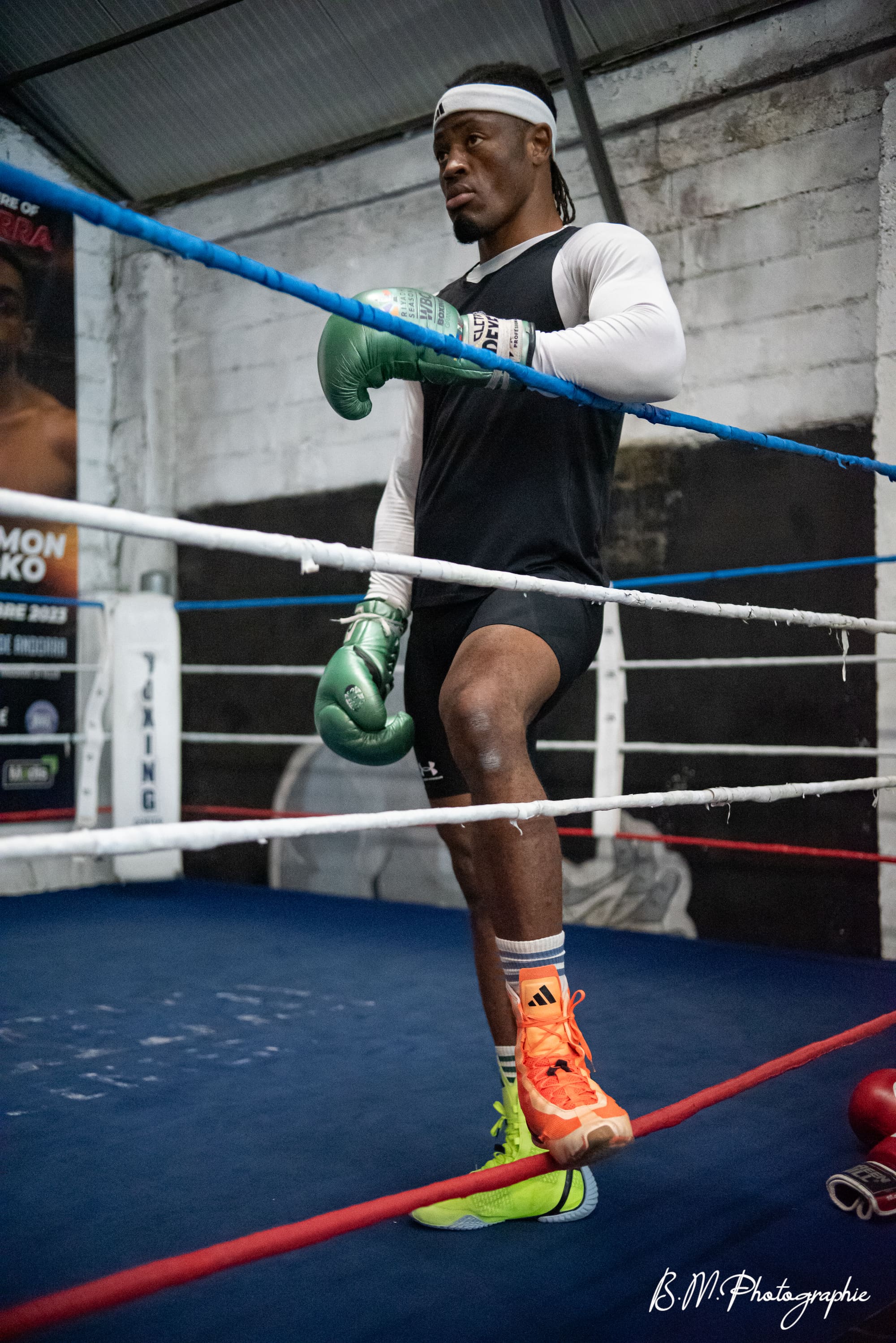 Un boxeur adossé aux cordes du ring, gants baissés, entre deux rounds.